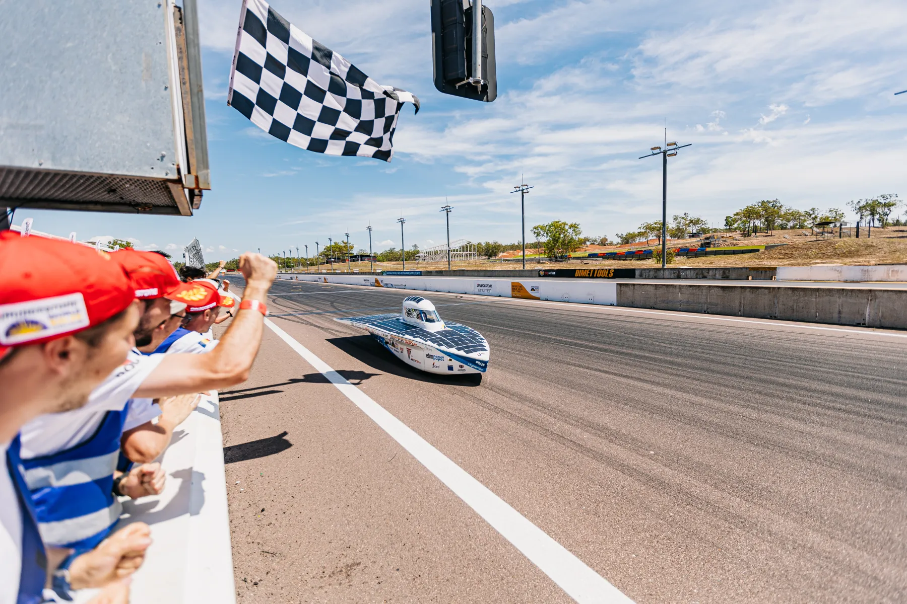 The Solis car crossing the finish line under the chequered flag