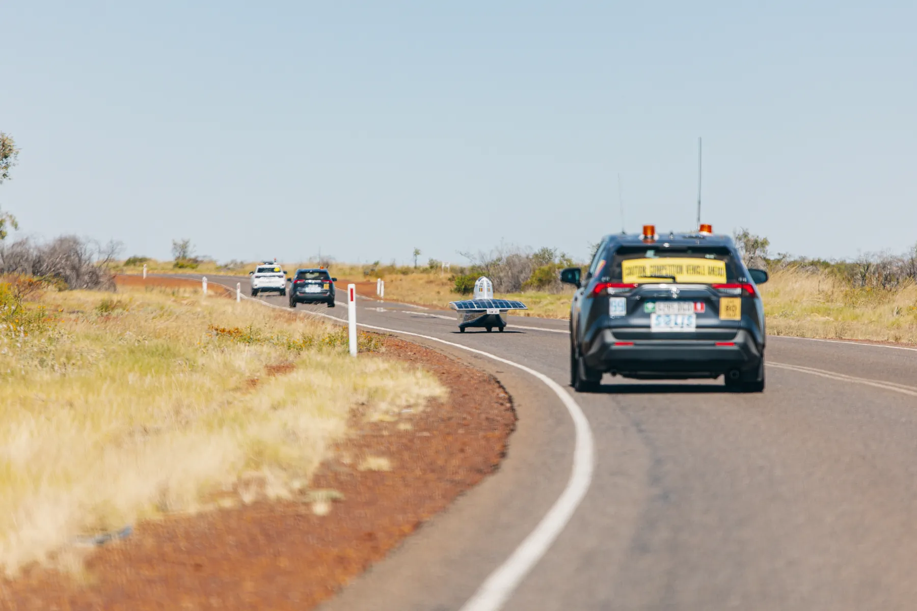 The solar car out on an Outback highway, led by the team's chase convoy